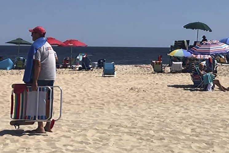 People walking and sitting on a sandy beach with the ocean in the background