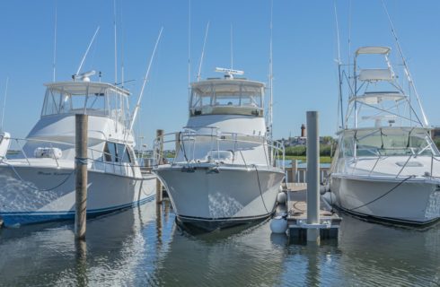 Three white mid-size boats in slips in the harbor