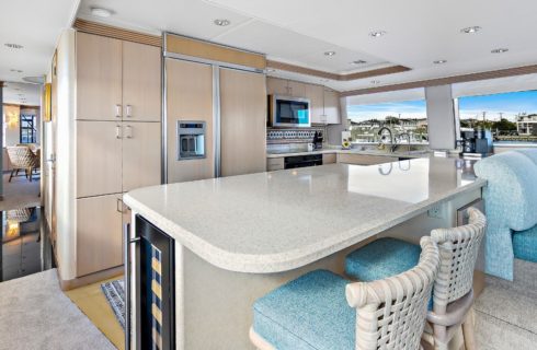 Kitchen on a yacht with light colored cabinets and countertops and bar stools