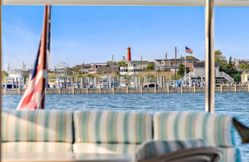 Deck on a yacht with light tan, blue, and white cushioned patio furniture with a view of the dock and harbor