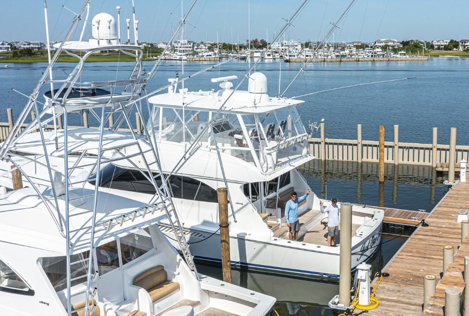 Two large white boats in the harbor with two people standing on a boat waving