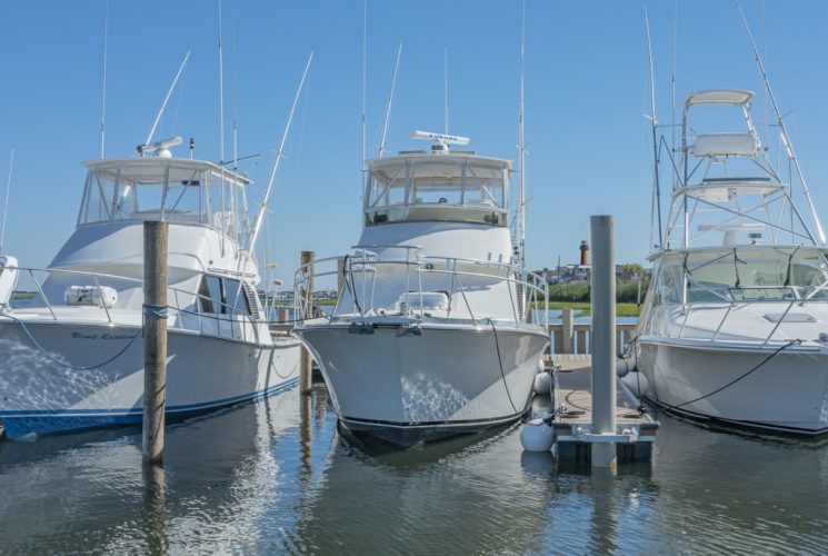 Three white mid-size boats in slips in the harbor