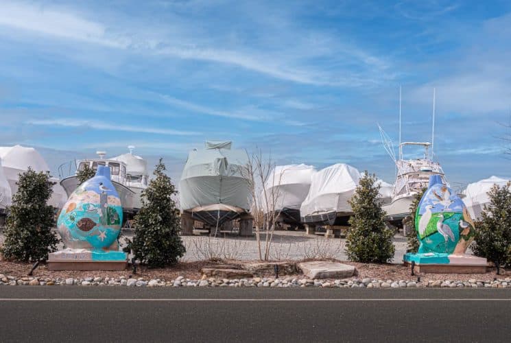 Multiple boats stored on dry land with covers