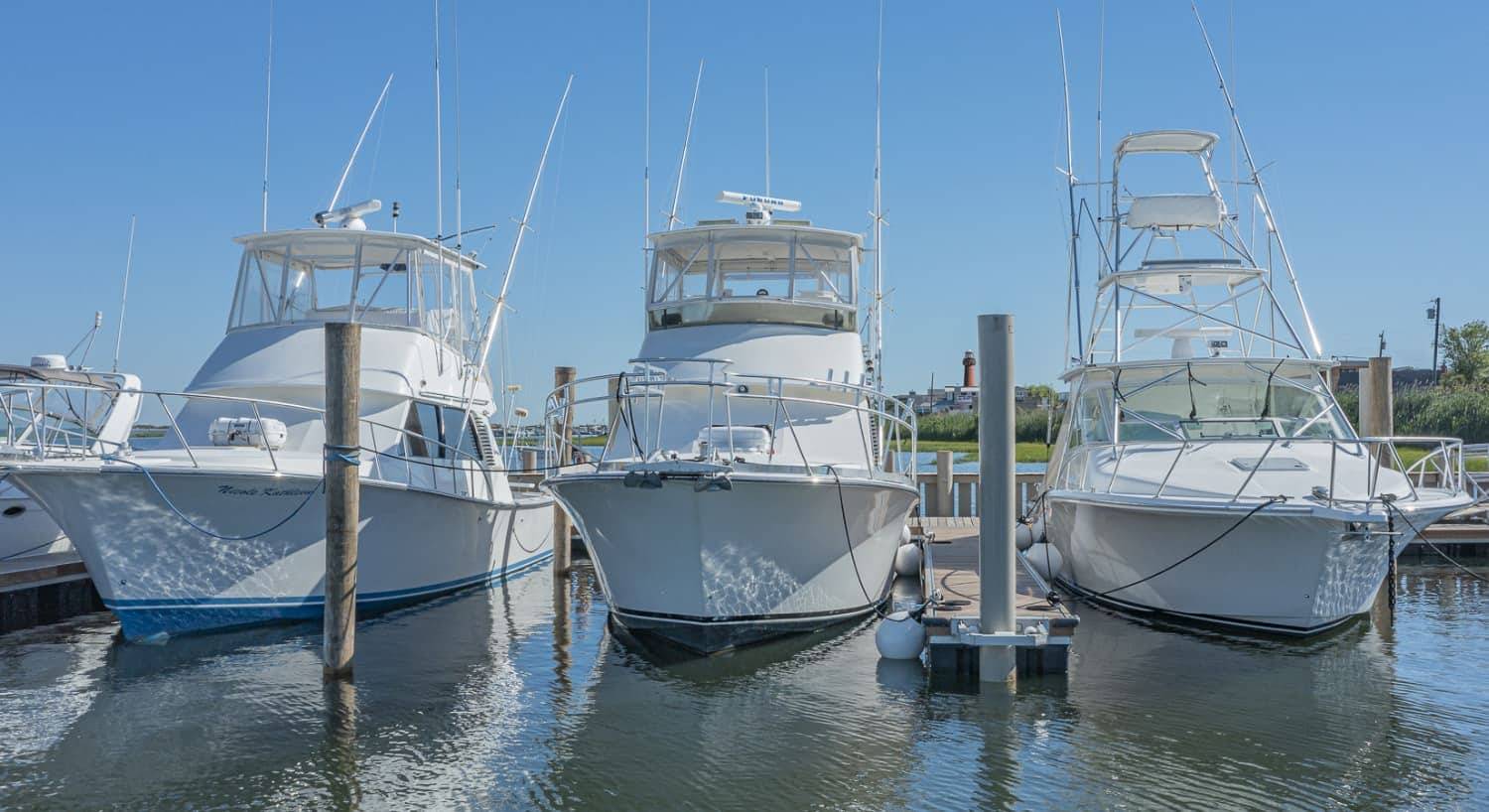 Three white mid-size boats in slips in the harbor