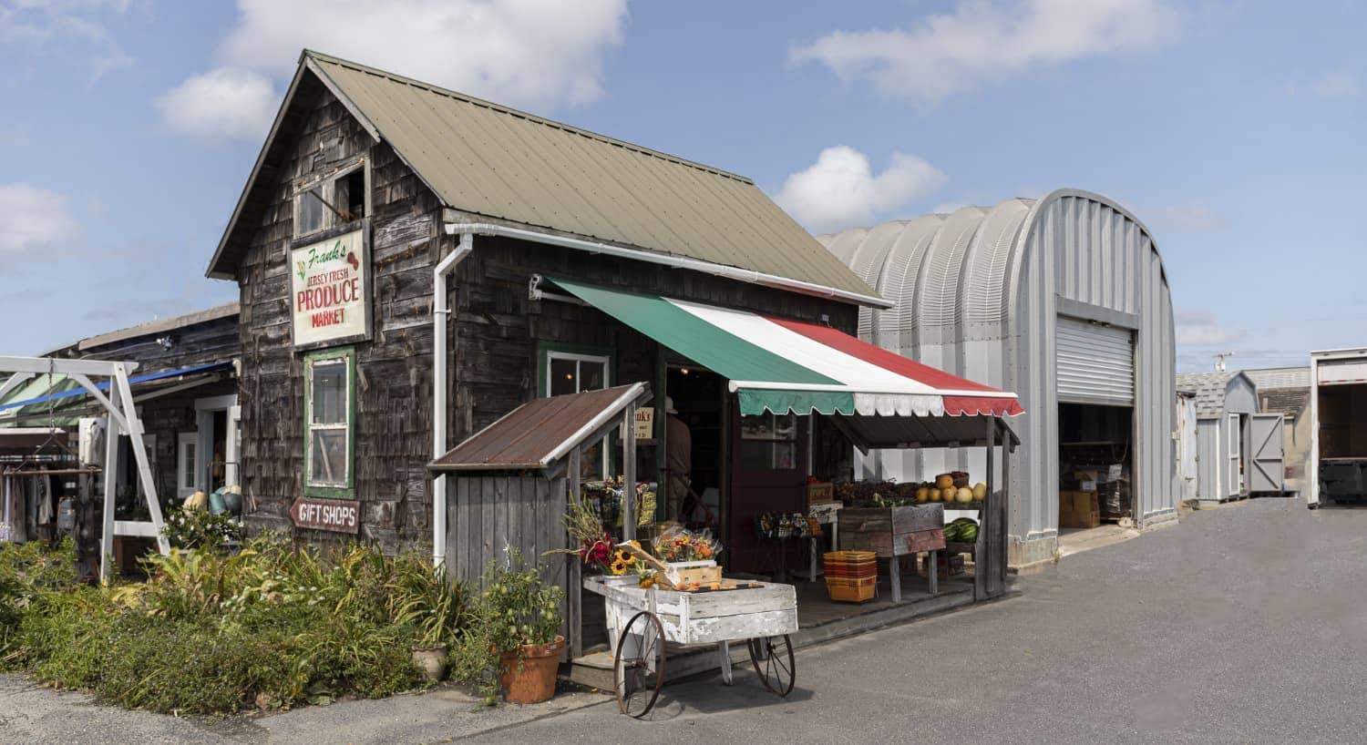 Small building selling produce and gifts with weathered cedar shake siding and green, white, and red awning